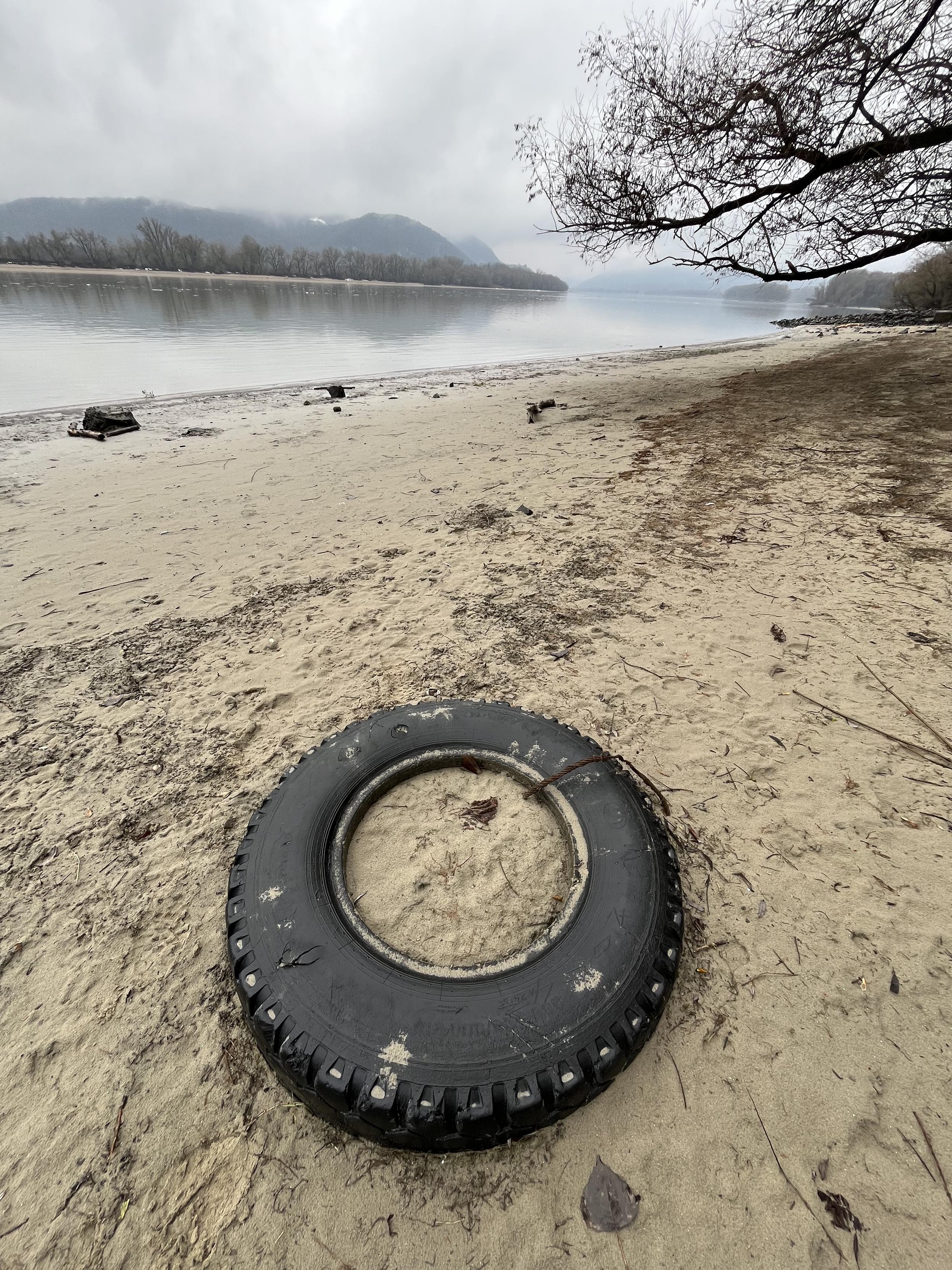 Car tire partly embedded a sandy riverbank.