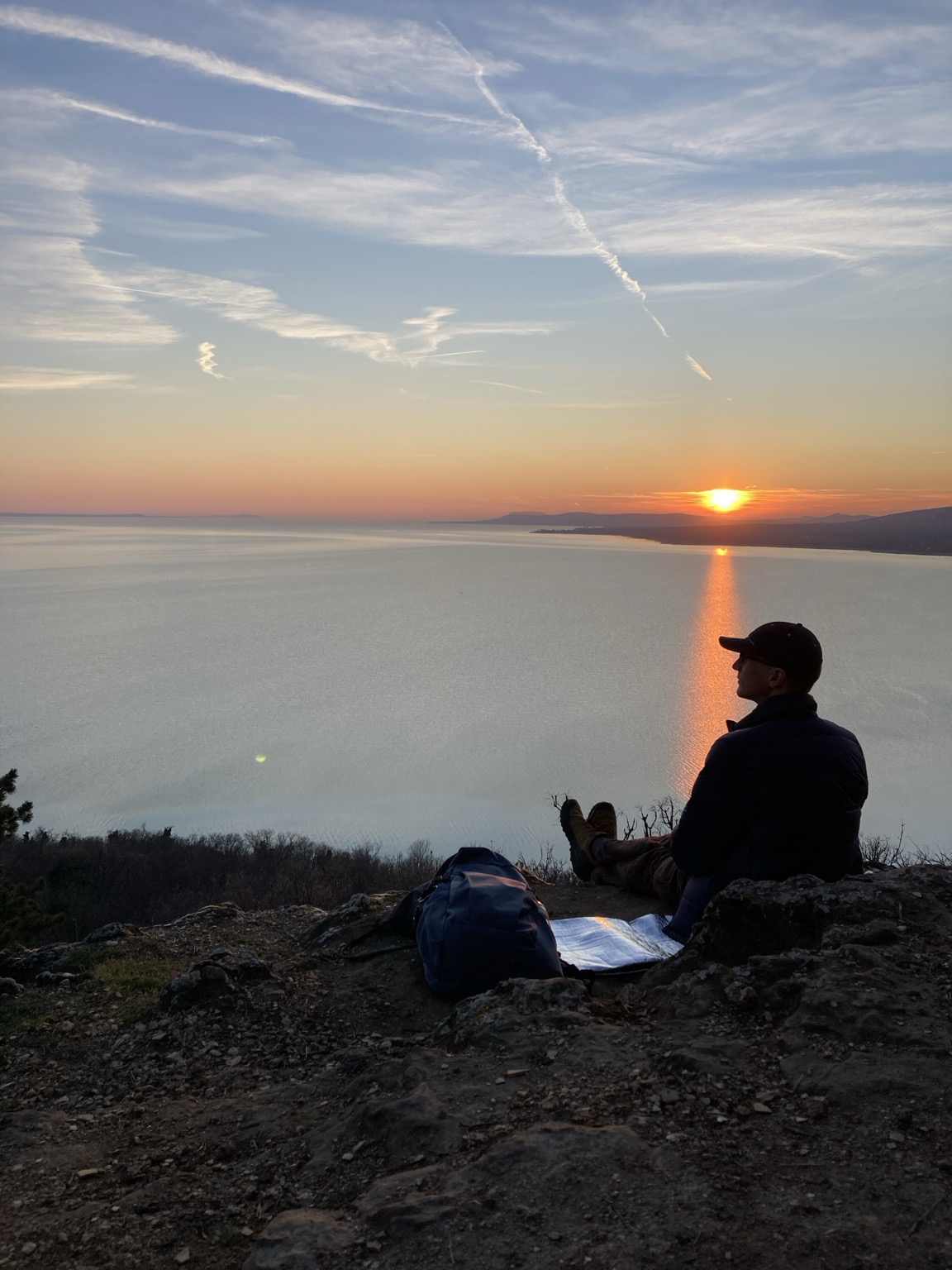 Me sitting with water Lake Balaton underneath, setting sun in the distance