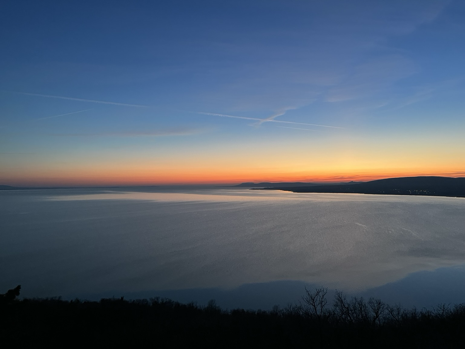 Sky later with orange glow over the horizon and the water appearing like glass