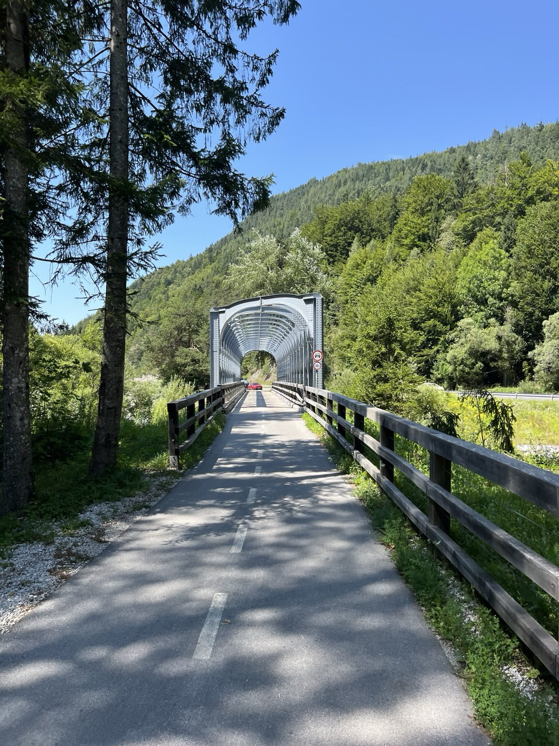 Bike path in the valley on a former railway, old steel bridge ahead